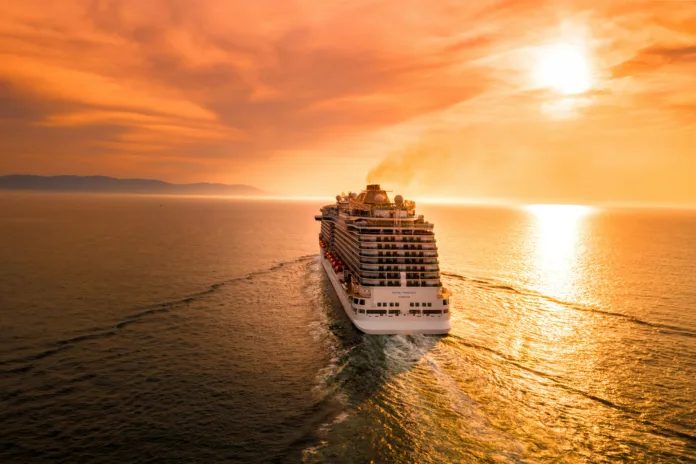 White cruise ship sailing into sunset