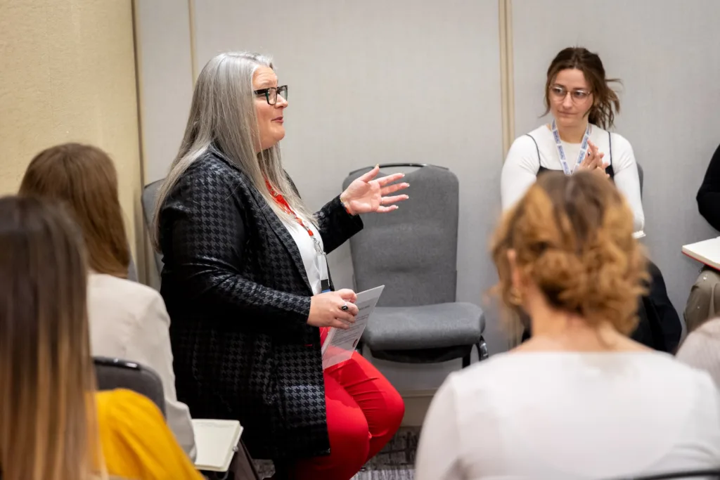 Steph Baldwin sitting and presenting to a group at the 2024 AFAAM