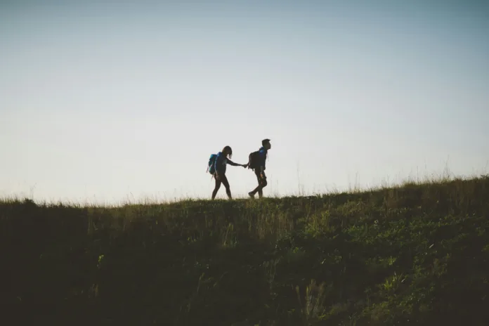Couple walking together holding hands along a hillside