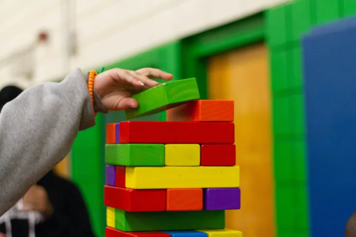 A hand placing a block on top of a tower of interwoven blocks