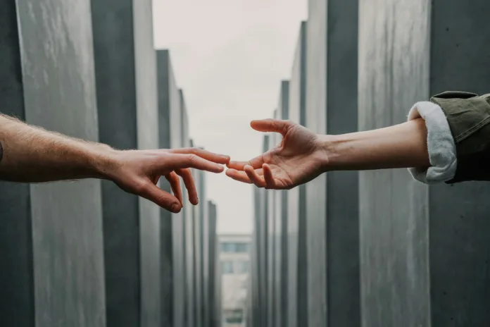 Two hands reaching between concrete pillars